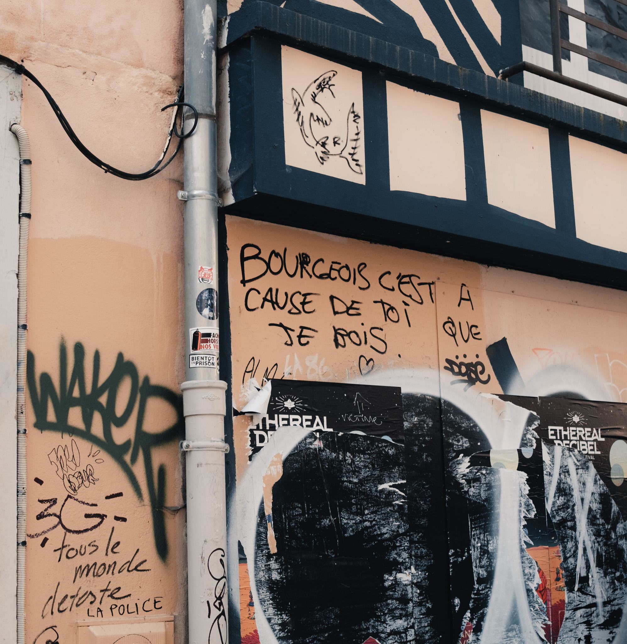 Photo of graffiti on a plaster wall, including a scrawled “Bourgeois c’est à cause de toi que je bois”